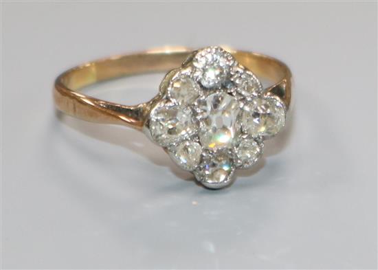 An early 20th century yellow metal and nine stone diamond cluster ring, size N.